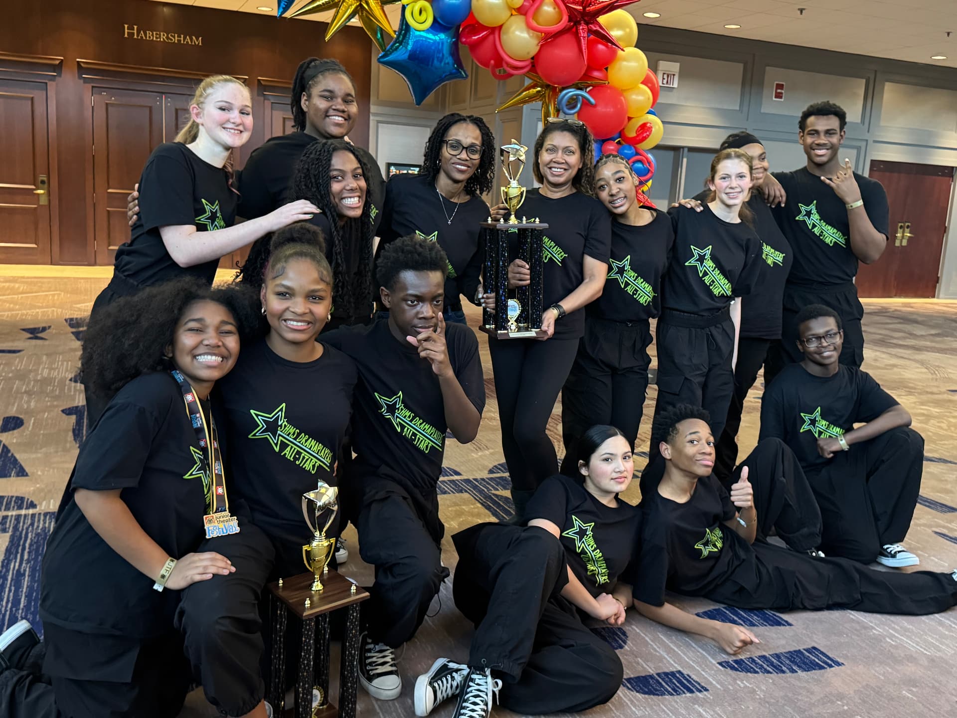 The cast and directors posing together with two Junior Theater Festival trophies