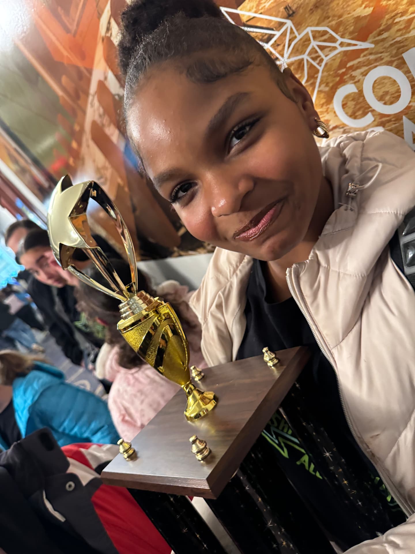 Asherah Anu holding a gold Junior Theater Festival trophy and smiling