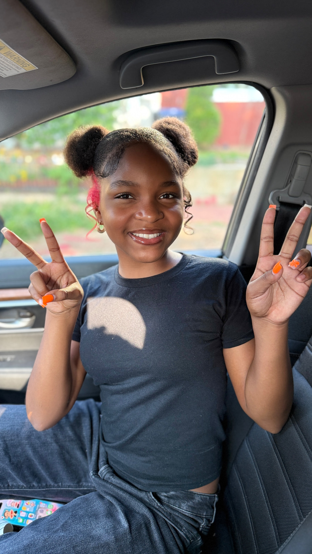 Asherah Anu Douglass smiling and throwing peace signs with both hands